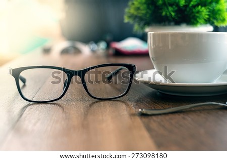 glasses and cup of coffee on wood desk vintage
