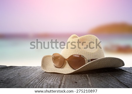 Sunglasses and hat on wood desk