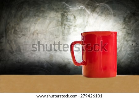 red coffee mug on wooden desk and polished concrete surface background