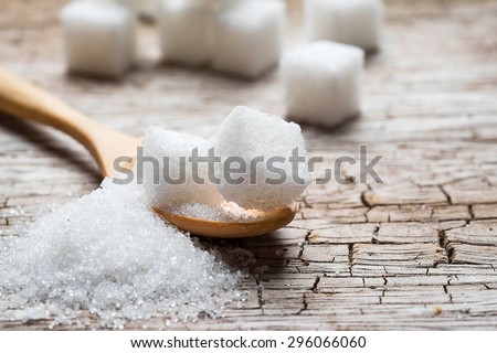 white sugar in wood spoon on wood table