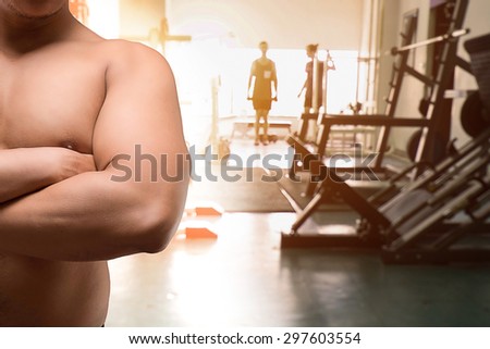 Fitness man cross arm with out shirt on fitness background