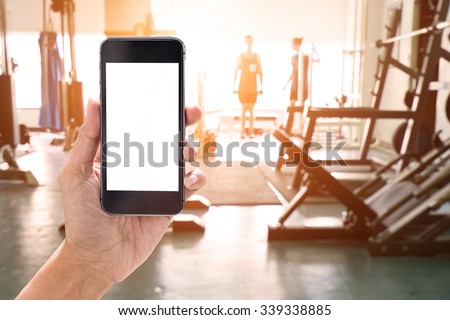 Hand holding smartphone device at gym background.