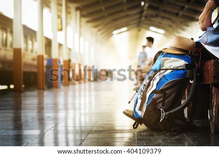 Backpack and hat at the train station with a traveler. Travel concept. Vintage tone.