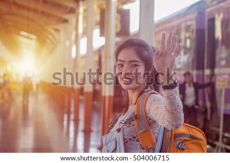 Young Asian girl say goodbye at train station before journey. Young Asian girl sent hand sign to goodbye.