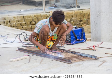 AYEYAWADY, MYANMAR - 13 JULY 2015 - At construction sit in Labuttar village welding worker working without any protection.