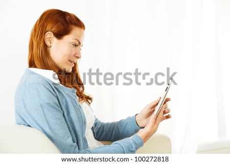 Close up portrait of a pretty young woman using a tablet PC on a light background