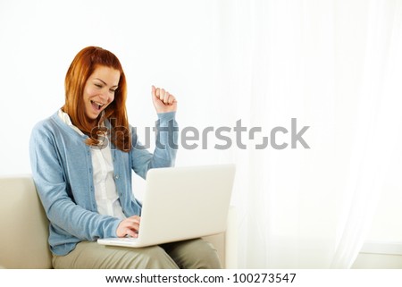 Portrait of a pretty young woman celebrating victory on laptop