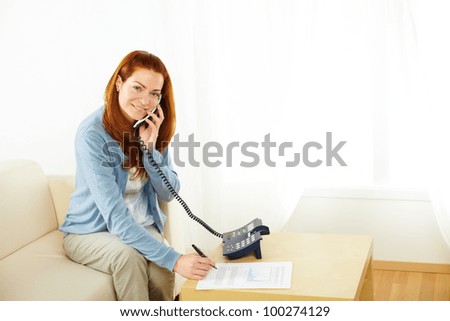 Portrait of a pretty young businesswoman working and talking at phone while looking at you