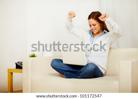 Portrait of a excited young lady celebrating a victory on laptop