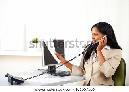Portrait of a young executive on phone while looking to documents