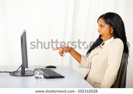 Portrait of a surprised business lady pointing the computer screen