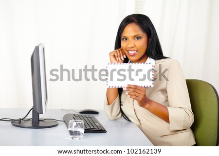 Portrait of a friendly young business lady at work showing a letter to you and smiling