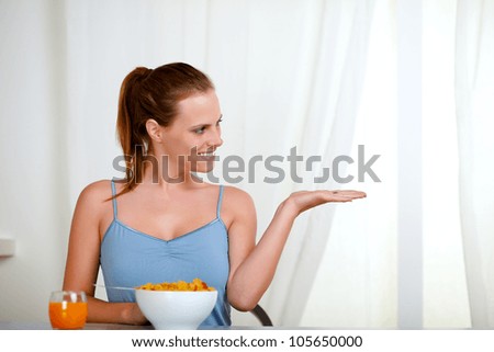 Portrait of a beautiful blonde woman eating healthy breakfast and looking to the right