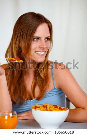 Portrait of a caucasian young woman smiling and eating healthy meal at home indoor