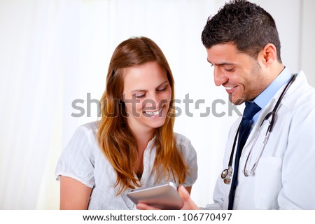 Portrait of a latin doctor and a patient woman looking something on tablet PC at hospital