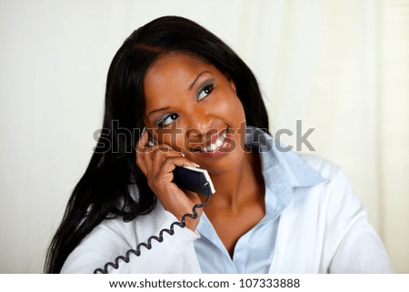 Close up portrait of a young black woman conversing on phone while is thinking and looking up