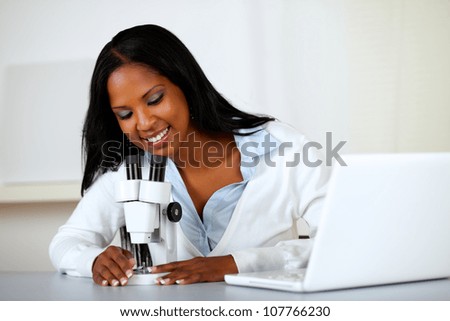 Portrait of an american black woman working with a microscope at soft colors composition