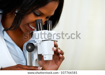 Portrait of a beautiful afro-american black woman using a microscope at soft colors composition