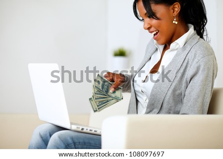 Portrait of a surprised woman with dollars looking to laptop