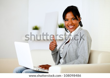 Portrait of a positive afro-american woman looking to you while is working on laptop and lifting the finger up
