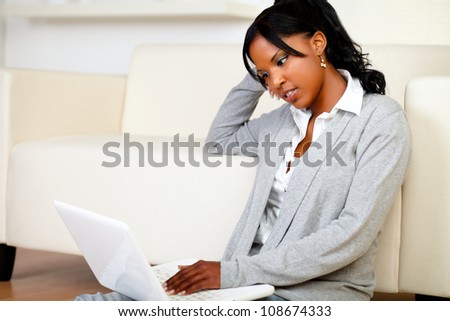 Portrait of a beautiful young woman working relaxed on laptop while is sitting on the floor at home