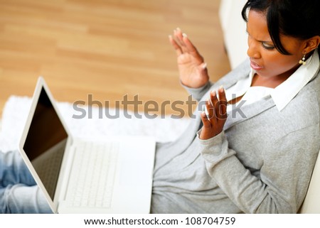 Top view portrait of a confused and surprised young woman reading a message on laptop screen while sitting on the floor at home indoor