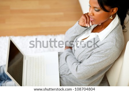 Top view portrait of a pensive attractive woman sitting on the floor in front of her laptop at home indoor