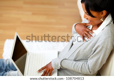 Top view of an surprised young woman reading a message on laptop screen while sitting on the floor at home indoor