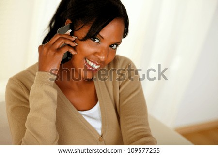 Top view portrait of an afro-American woman conversing on mobile phone while is looking to you
