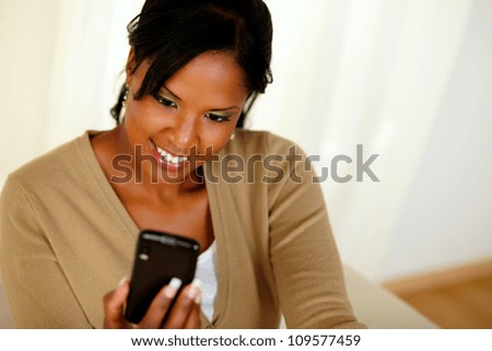 Top view portrait of a charming black lady sending a message by cellphone