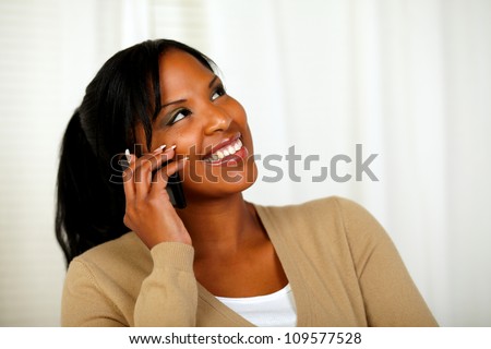 Portrait of a pretty woman looking up while talking on cellphone at home indoor