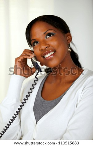 Portrait of a black woman looking up while talking on phone at soft colors composition