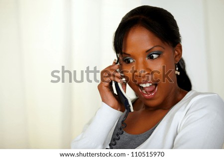 Portrait of an excited young woman screaming and talking on phone at soft colors composition