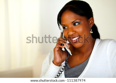 Portrait of an afro-American woman conversing on phone at soft colors composition. With copyspace