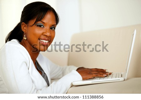 Portrait of a stylish girl looking at you while working on laptop at home indoor. With copyspace
