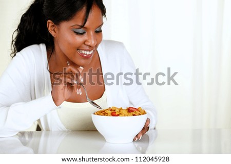 Portrait of an afro-american female eating a bowl of cereals with strawberries at soft colors composition. with copyspace