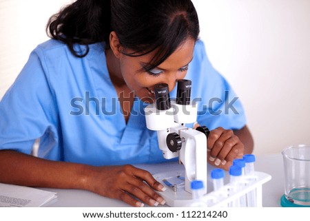 Scientific woman in blue uniform using microscope at laboratory