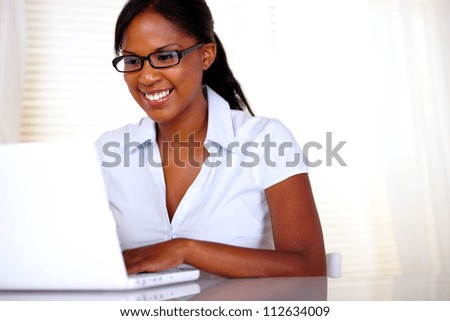 Smiling woman with black glasses working on laptop at office - copyspace