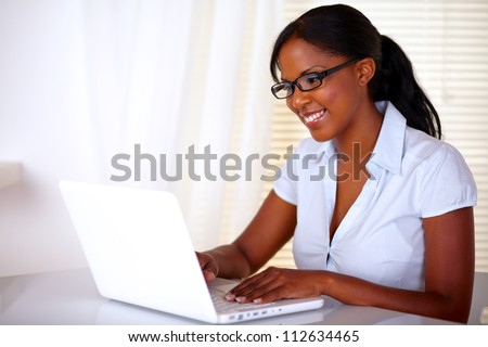 Stylish young woman with black glasses working on laptop at workplace - copyspace
