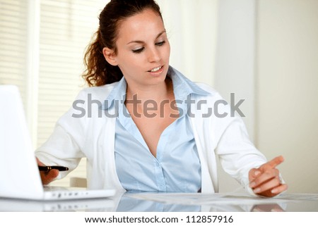 Stylish secretary working on laptop with documents at office
