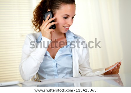 Pretty businesswoman conversing on cellphone at office