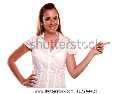 Charming blonde young woman pointing to her left looking at you against white background - copyspace