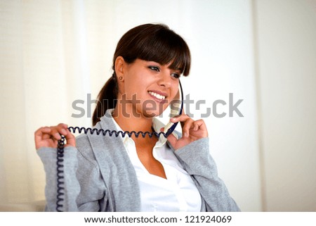 Portrait of a lovely young woman smiling and conversing on phone at soft colors composition