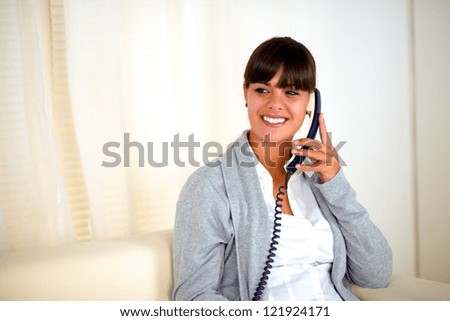 Portrait of an attractive young woman conversing on phone sitting on couch