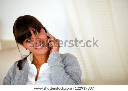 Portrait of a young woman speaking on cellphone looking to her left up - copyspace