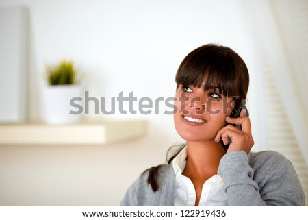 Portrait of a young woman speaking on cellphone looking to her right up