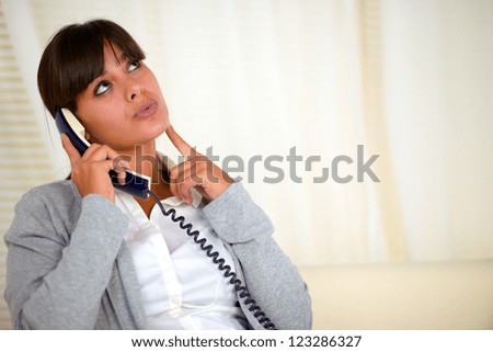 Portrait of a pensive woman looking up while speaking on phone - copyspace