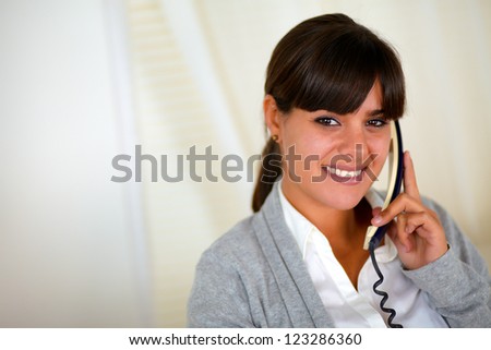 Portrait of a latin young woman speaking on phone and looking at you - copyspace