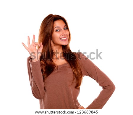 Portrait of a smiling young woman saying great job with her hand against white background