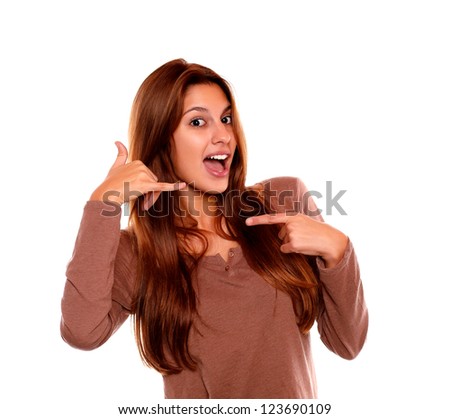 Portrait of a young woman looking at you saying call me and pointing to her right on isolated background